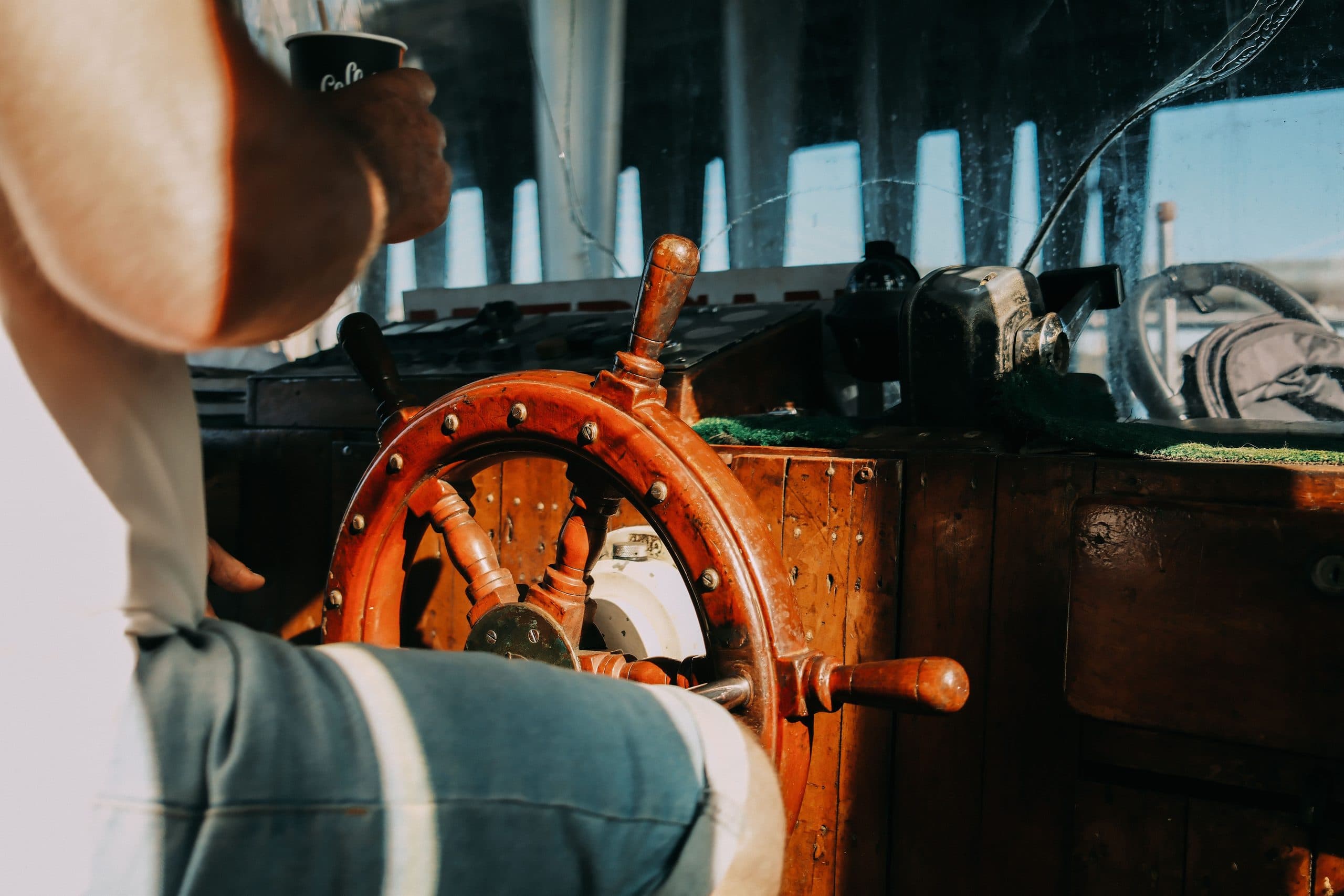 Hands on the wooden wheel of a sailing ship